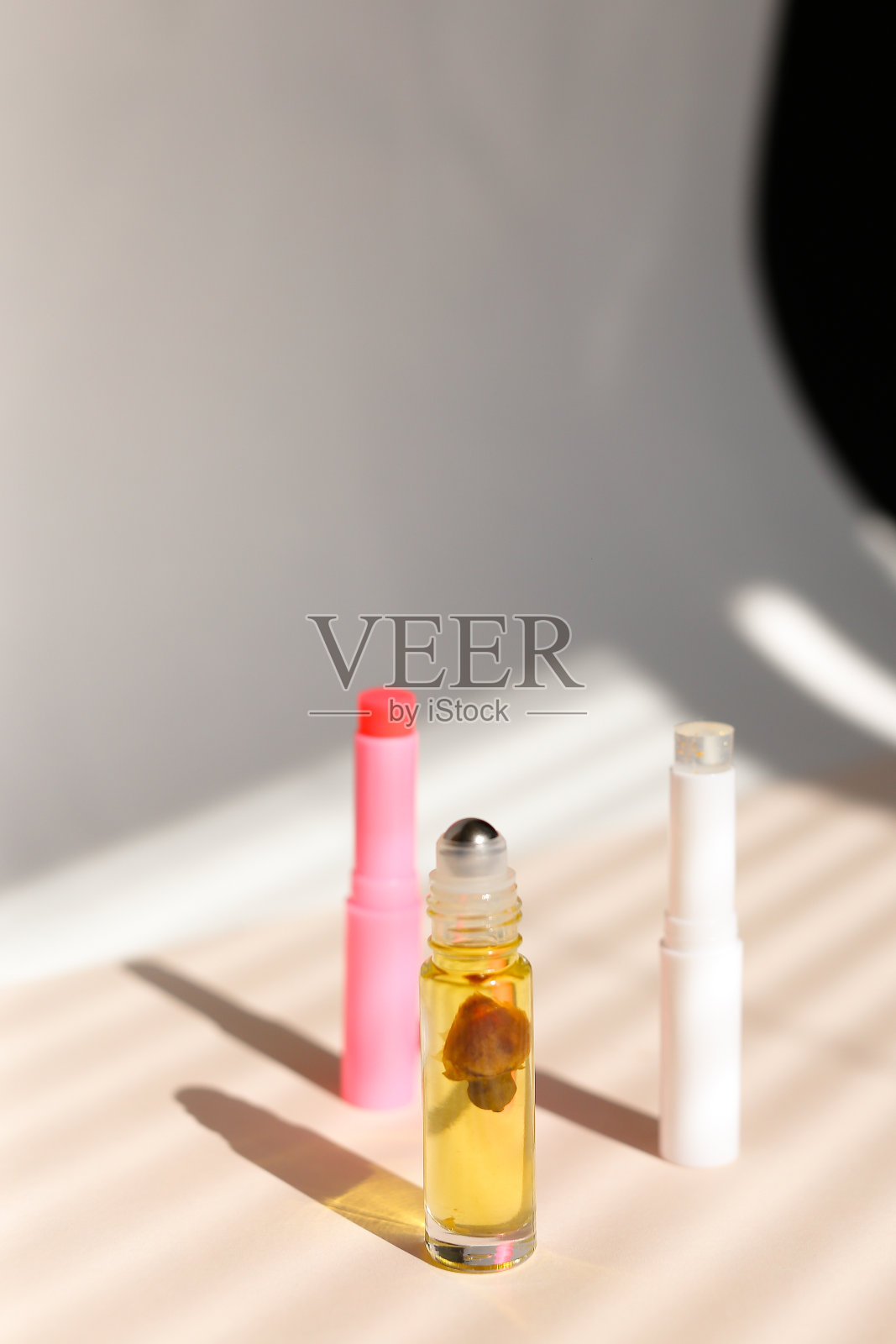 香水滚轴瓶和卫生口红条纹阴影背景照片摄影图片