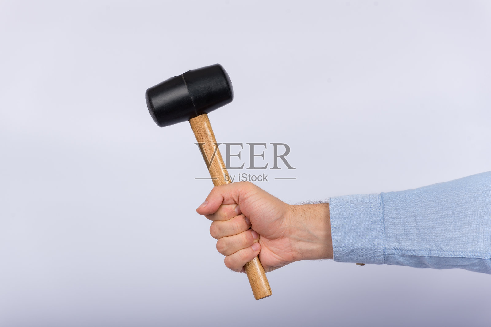 男性手持锤子，背景为白色。侧视图照片摄影图片