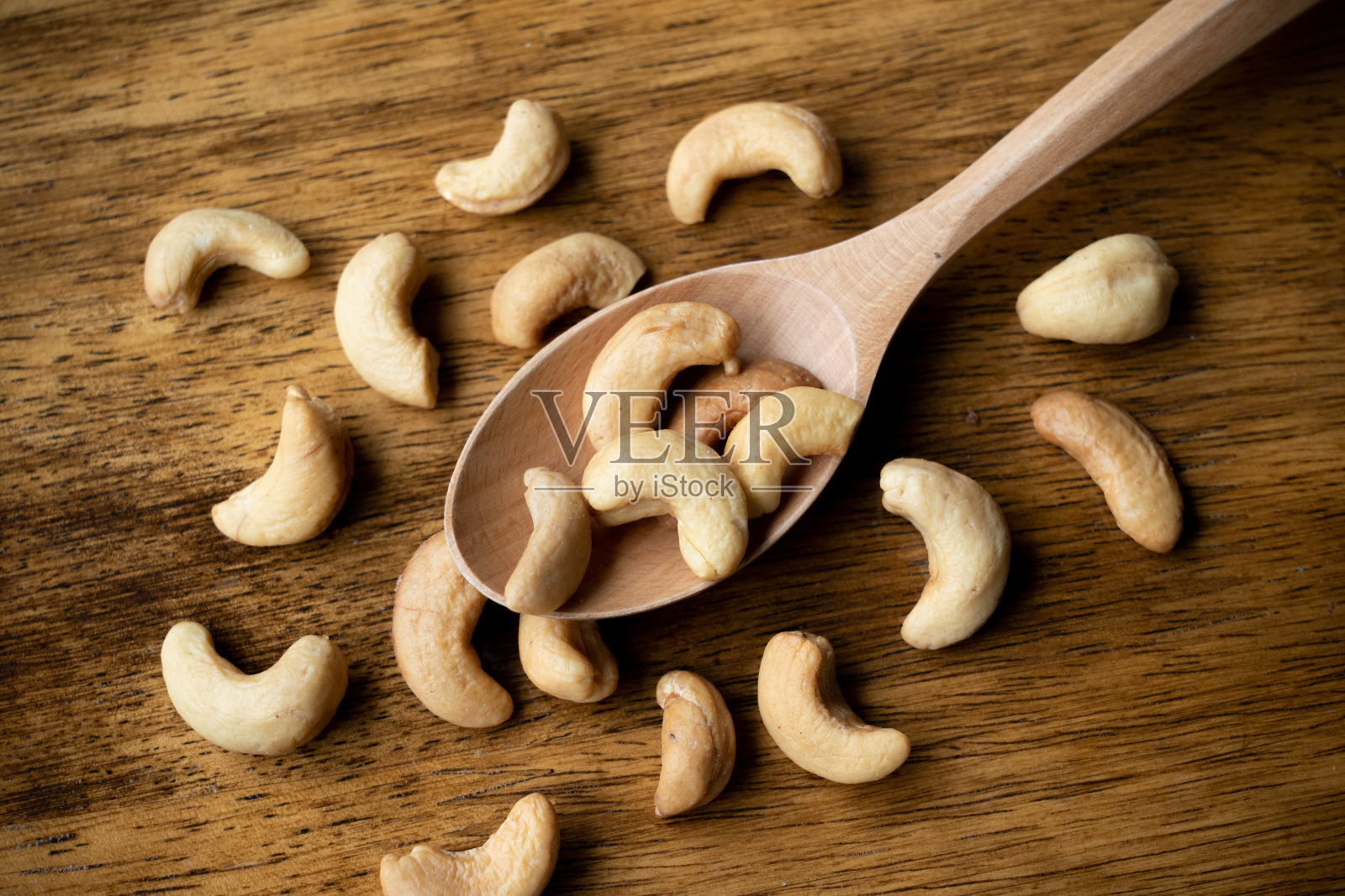 美味的腰果放在木勺上。选择性地关注一些腰果。照片摄影图片