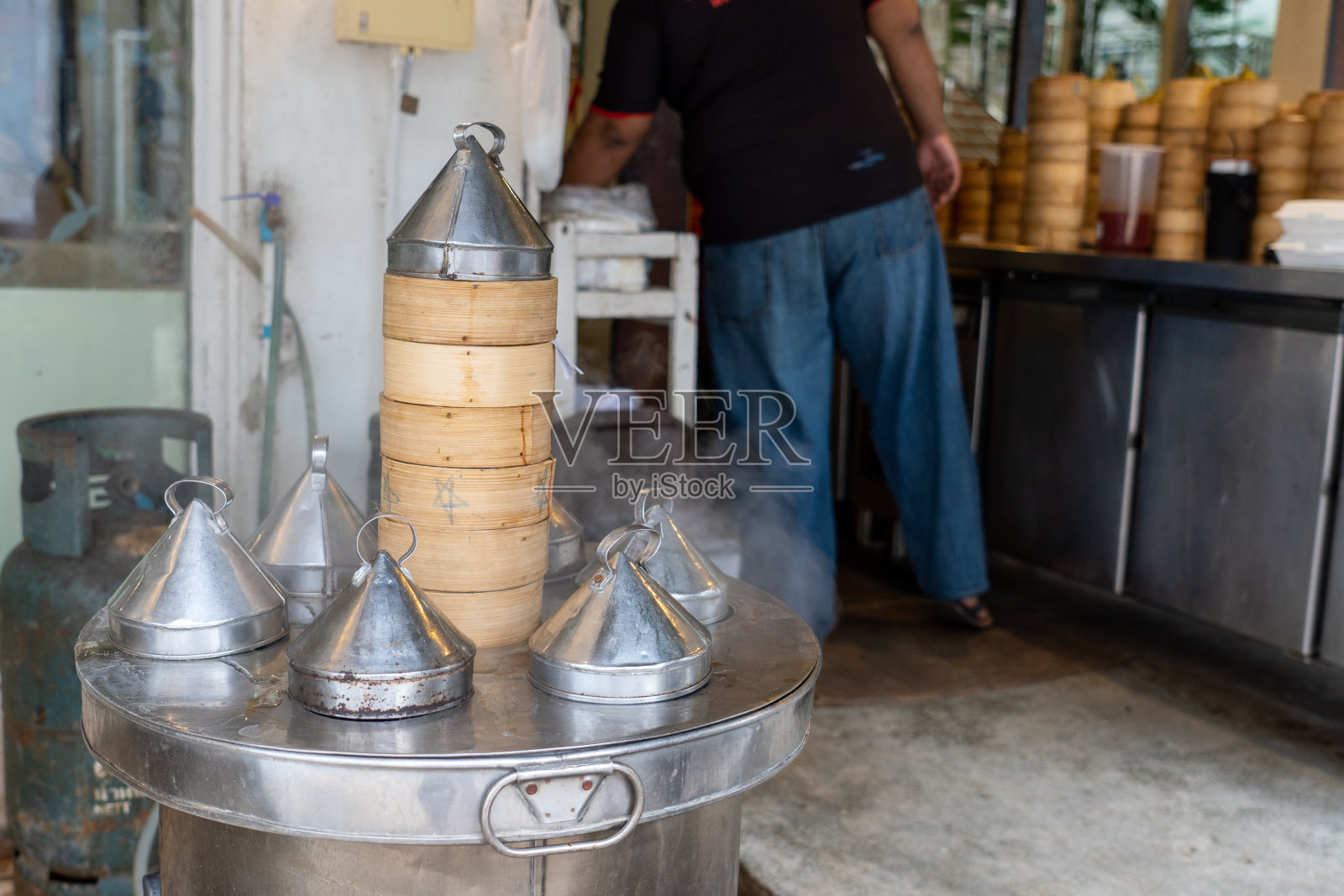 不锈钢蒸笼里的竹篮。照片摄影图片