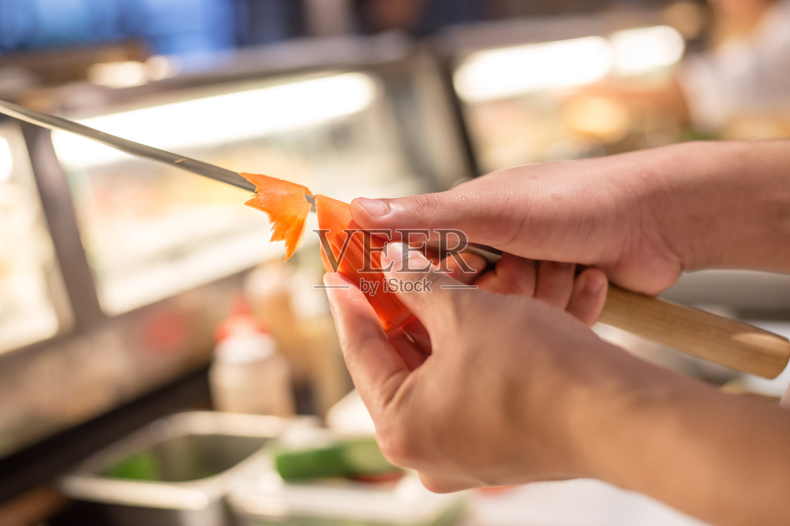 专业厨师双手雕刻胡萝卜，为菜肴装饰做准备。照片摄影图片