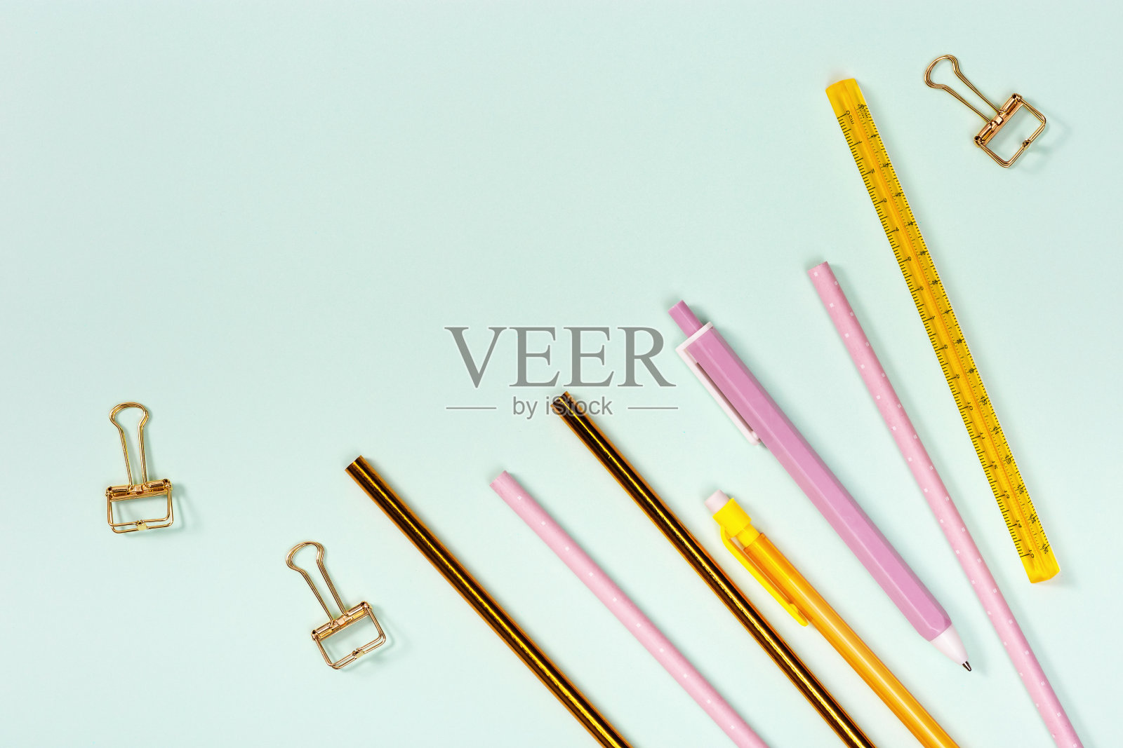 平铺学校或办公室用文具。粉色和金色的铅笔，钢笔和金属回形针。学校设备。顶部视图与复制空间。照片摄影图片