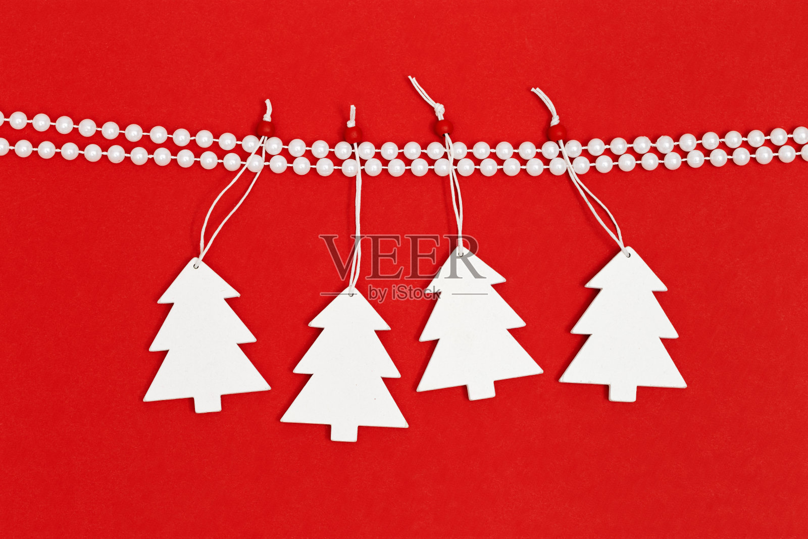 圣诞树上挂着白色的装饰物，点缀着明亮的红色背景。新年或圣诞的概念。寒假的象征。照片摄影图片