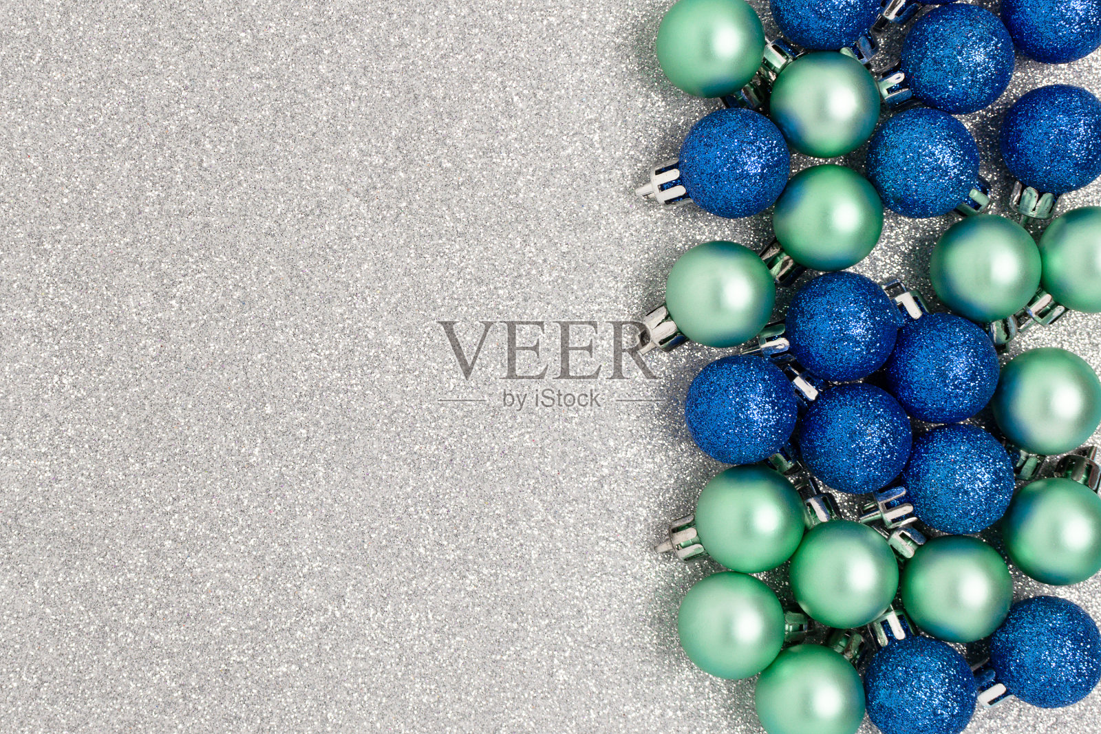 在银色闪亮的背景上用圣诞小装饰品做成的框架。照片摄影图片