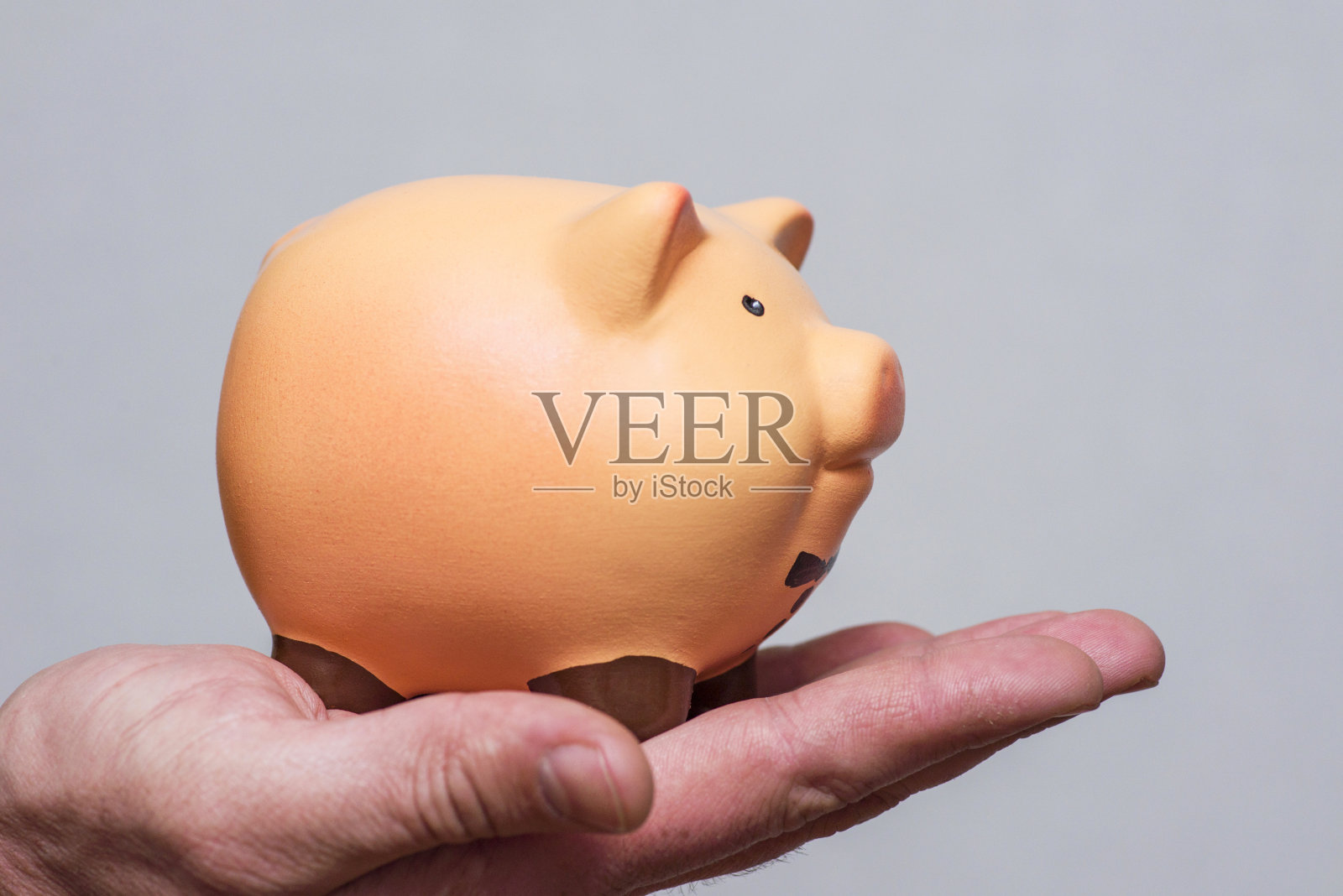 手里拿着存钱罐的男人。男人手里拿着一个存钱罐，用来表达金钱或金融概念照片摄影图片