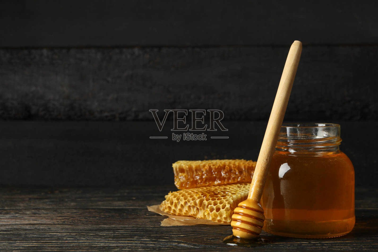 蜂巢，盛有蜂蜜的罐子和木色背景的勺子照片摄影图片