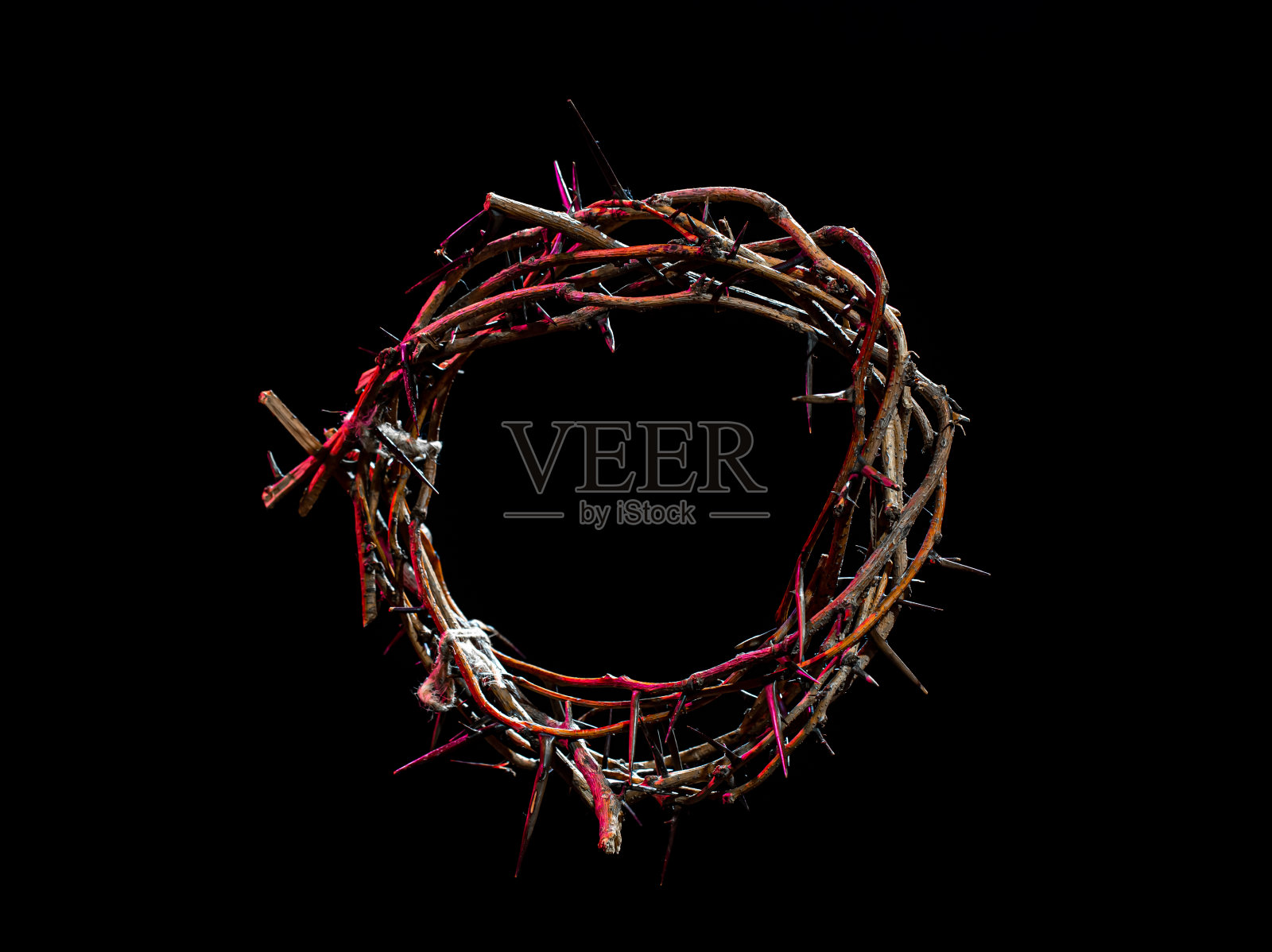 荆棘的王冠躺在一个孤立的黑色背景上，有一抹红色的光。圣周的概念，与痛苦和爱联系在一起。照片摄影图片
