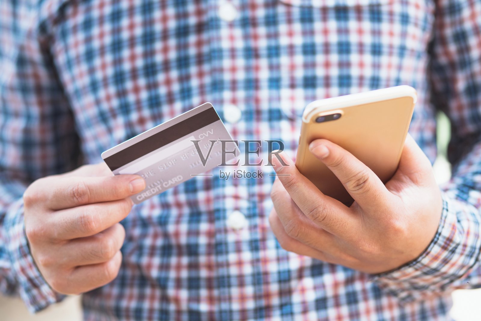 在线购物。拿着信用卡用智能手机的男人。照片摄影图片