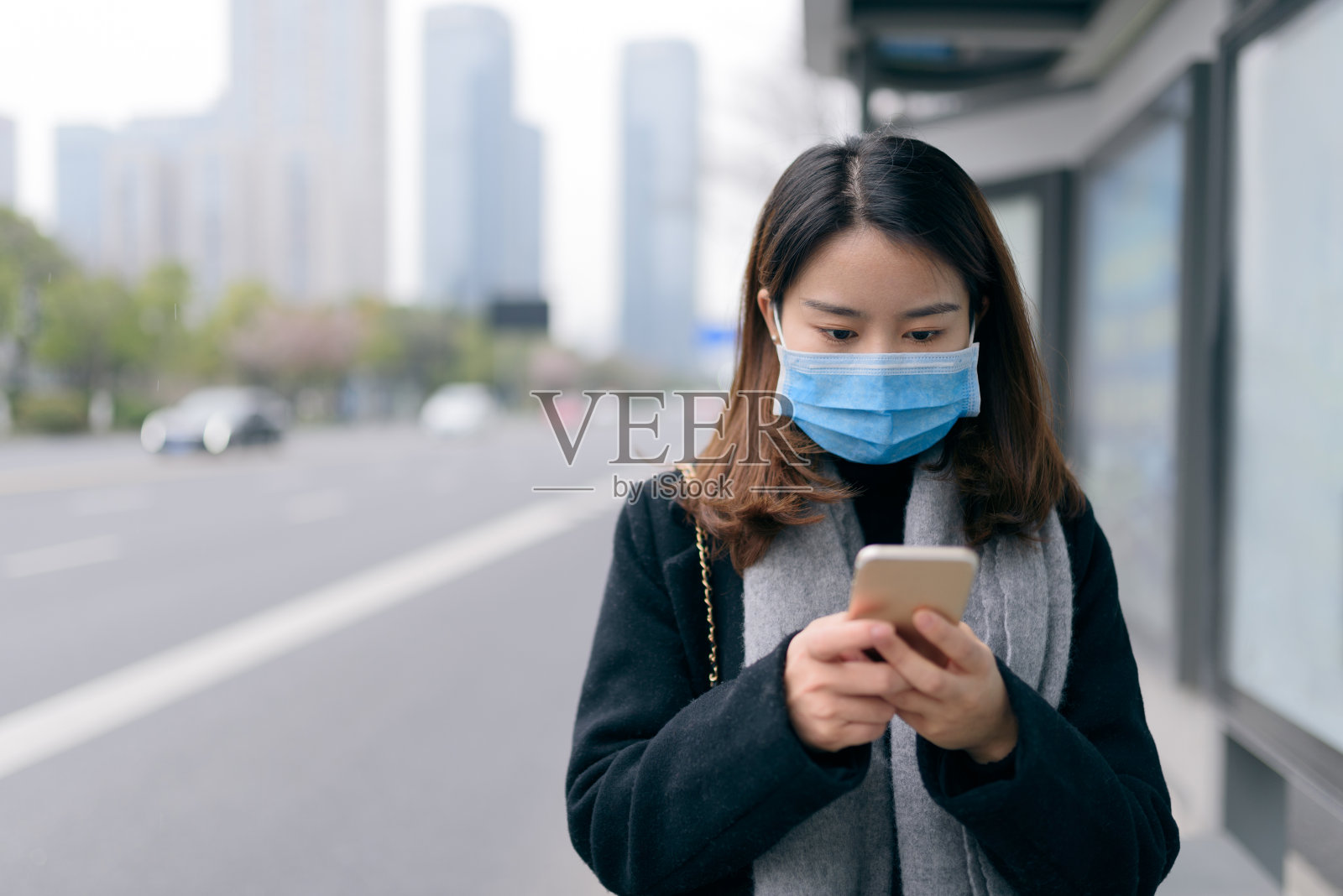 年轻的亚洲华人妇女戴着口罩，在街上打电话。照片摄影图片