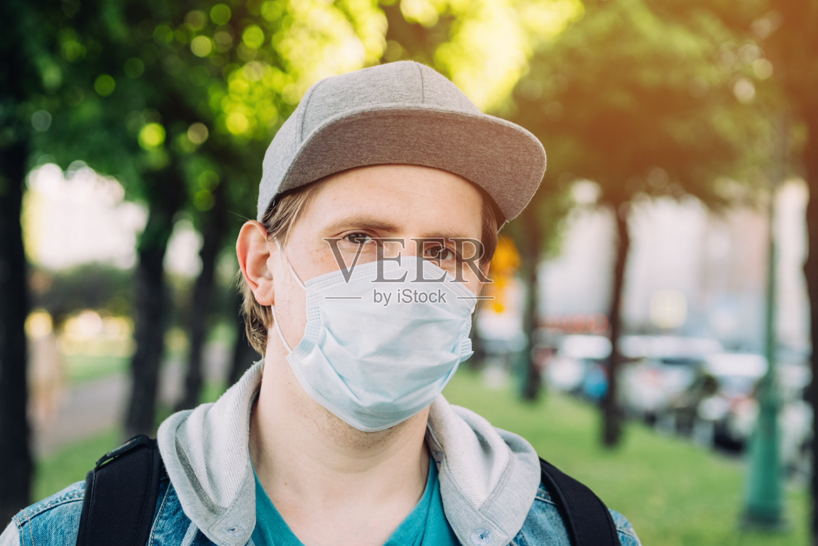 一幅在城市流行期间戴着医用口罩和帽子的白人男子的肖像。新常态照片摄影图片