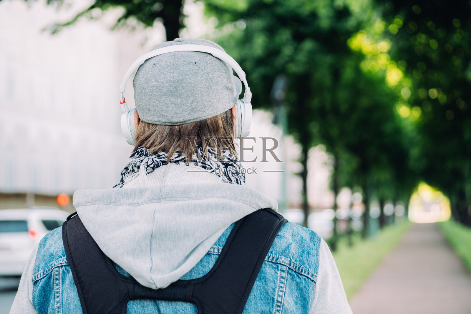 一名戴着灰色帽子的白人男子戴着耳机穿过公园照片摄影图片