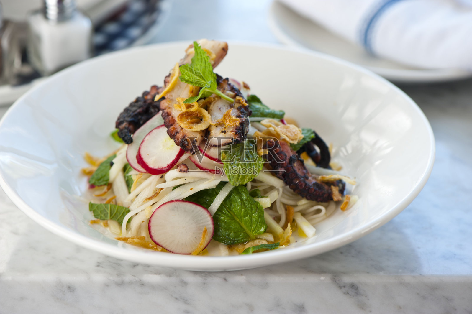 烤章鱼。用橄榄油、黄油和大蒜煎烤章鱼，配以葱和意大利欧芹，并配以柠檬。经典的意大利，美国餐厅或法国小酒馆的主菜或开胃菜。照片摄影图片