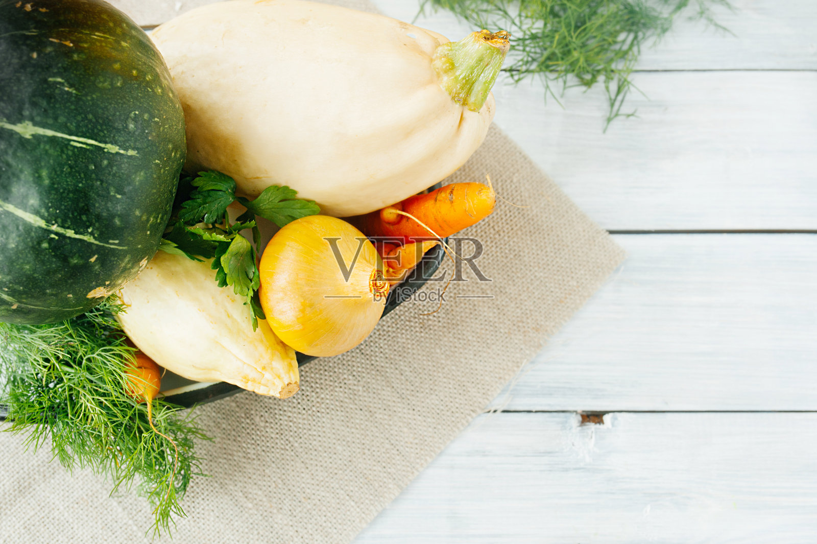 从花园里摘来的生蔬菜，西葫芦、胡萝卜、绿南瓜、洋葱、莳萝和欧芹放在白色的木桌上，是收割的时候了照片摄影图片