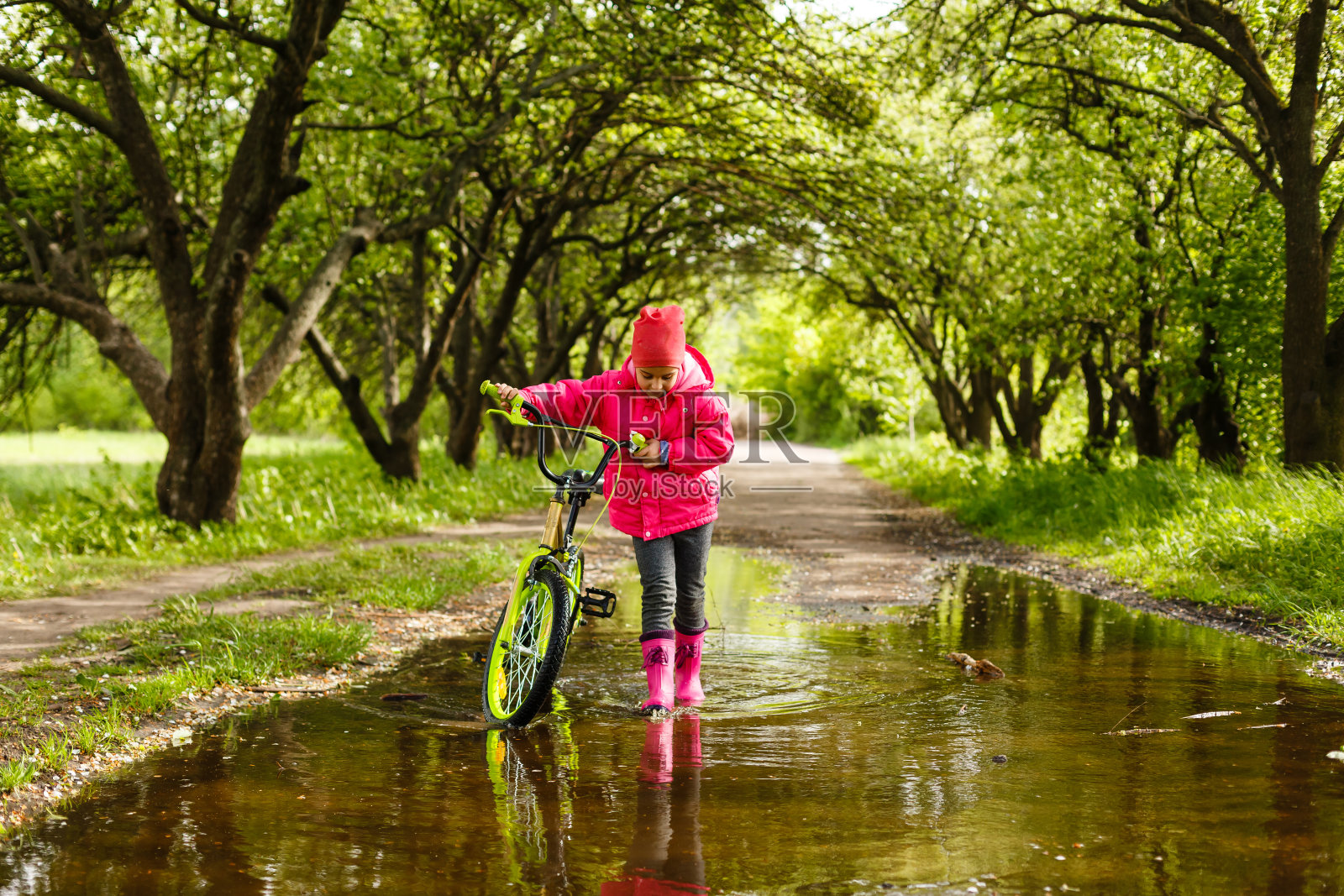 小女孩在水坑里骑自行车照片摄影图片