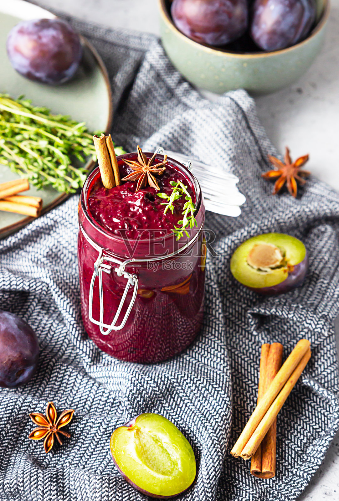 在灰色的背景上加入一罐香辣梅子酱、肉桂、八角和百里香。照片摄影图片