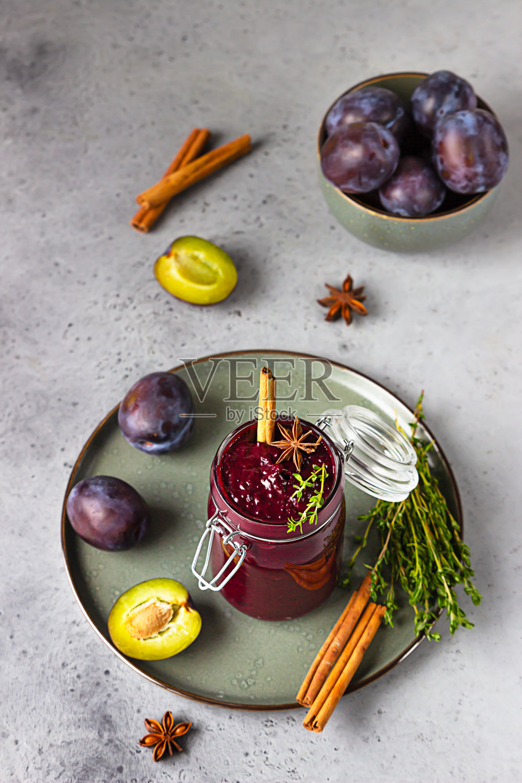 甜的自制辣酱李子，水果，百里香和香料在灰色的石头桌上。前视图。照片摄影图片