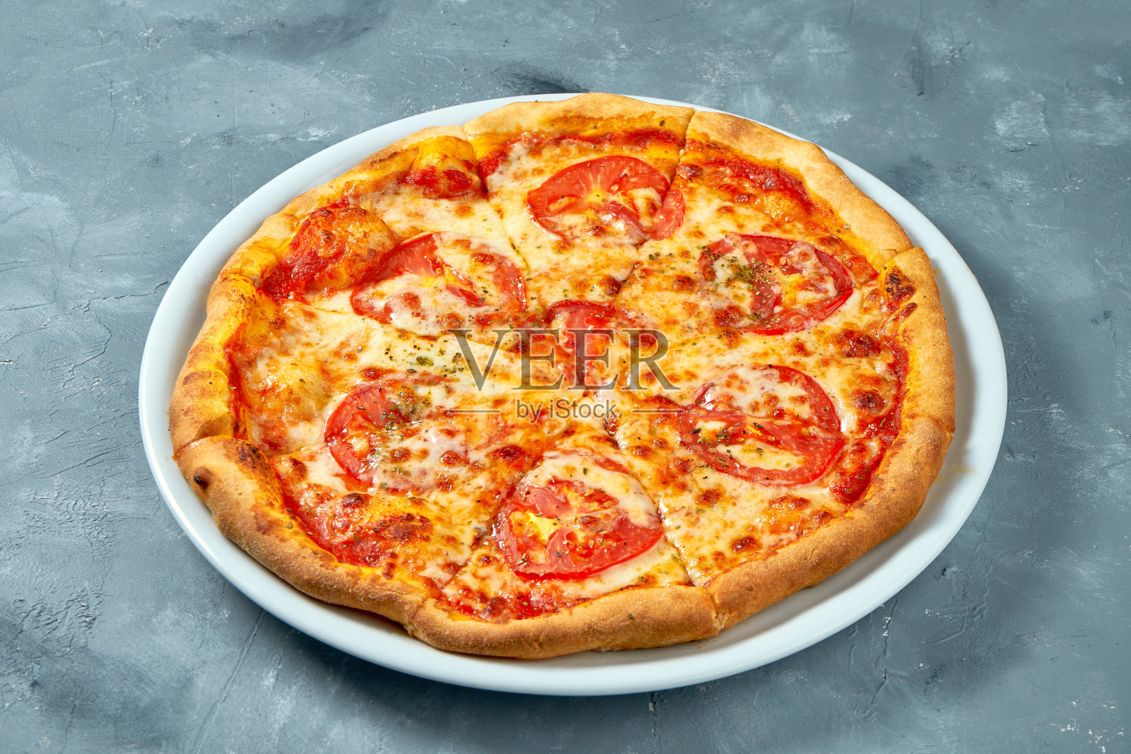 经典的意大利玛格丽塔披萨配西红柿和奶酪，白色盘子，混凝土背景照片摄影图片