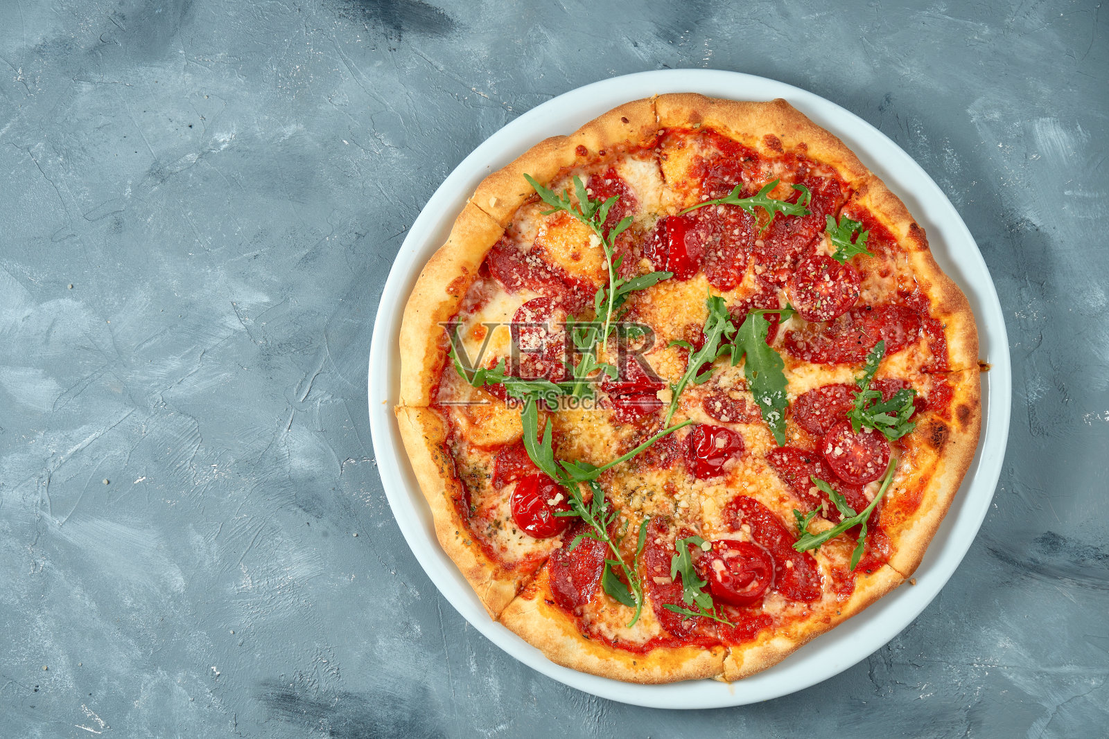 白色盘子上的意大利披萨，有意大利腊肠、芝麻菜和帕尔马干酪。具体的背景。前视图。本空间照片摄影图片