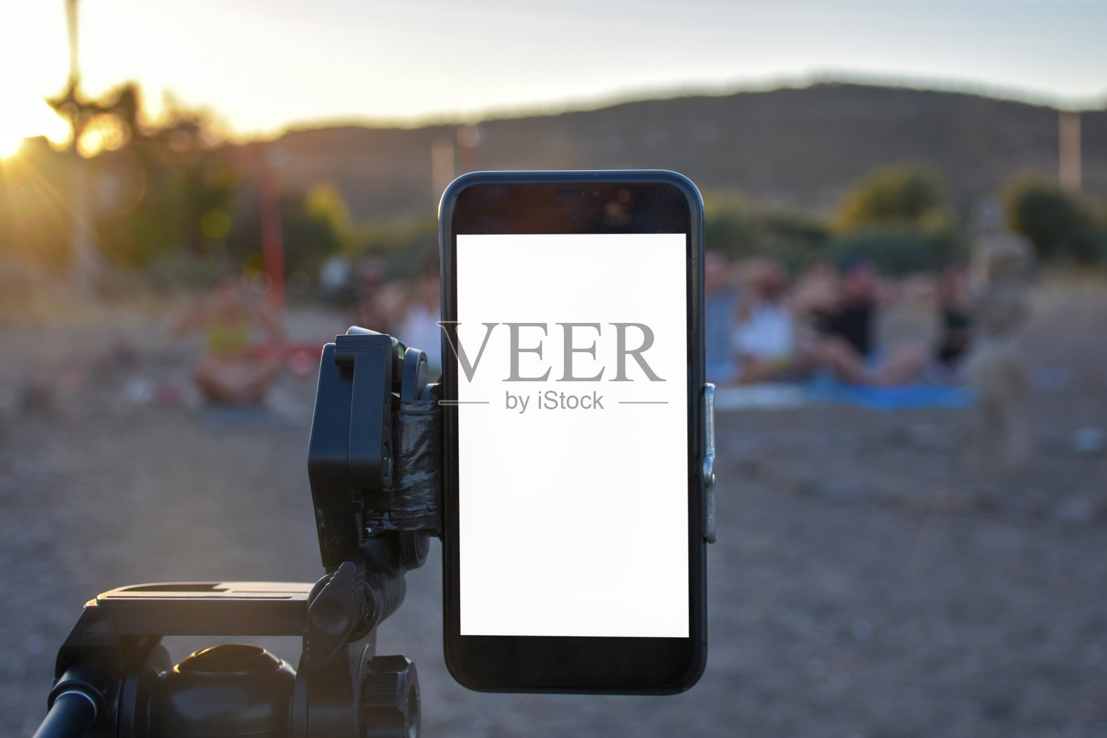 黑屏智能手机记录人们做瑜伽在日落，屏幕与剪切路径照片摄影图片