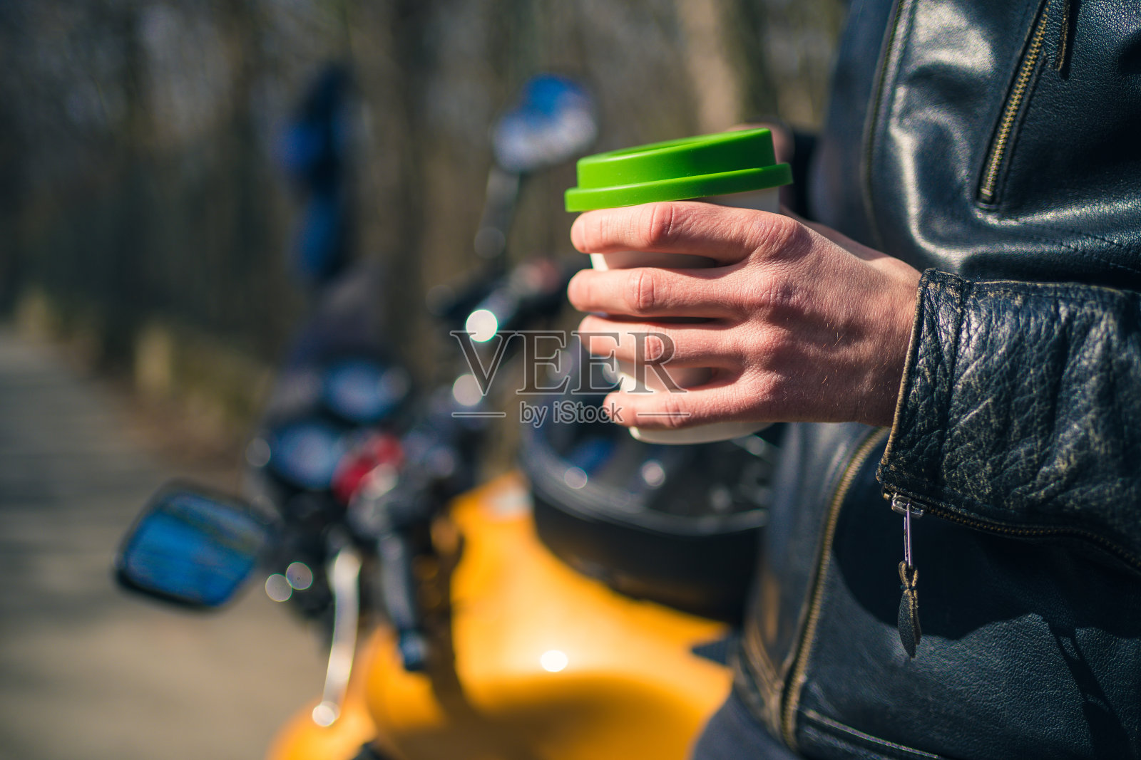 拿着咖啡杯坐在摩托车上的男人照片摄影图片