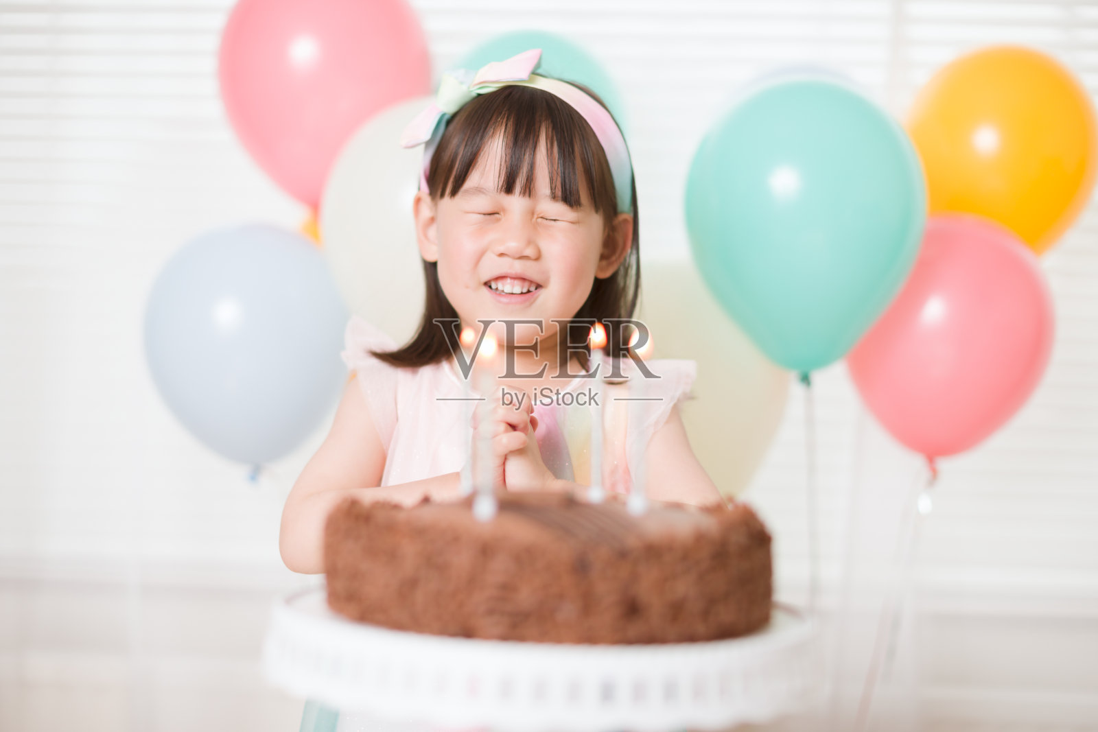蹒跚学步的小女孩在庆祝她四岁生日时许了一个愿望照片摄影图片