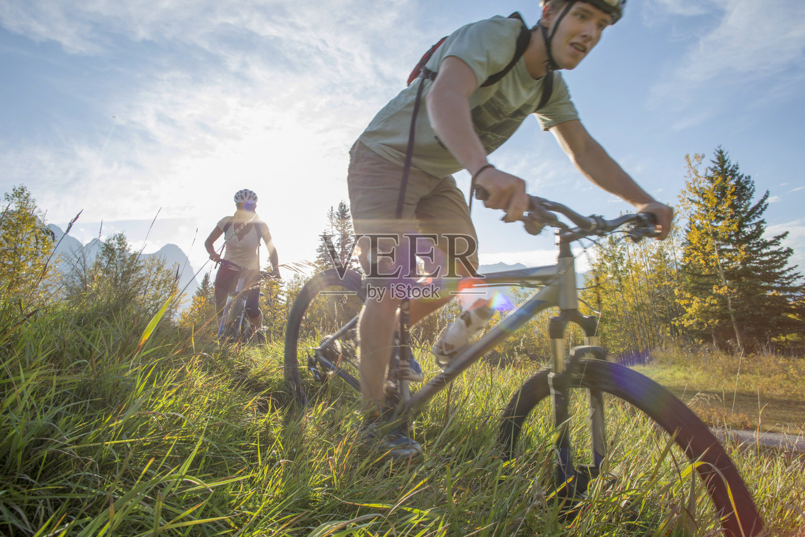 在秋天，骑山地车的人沿着长满草的小路骑行照片摄影图片