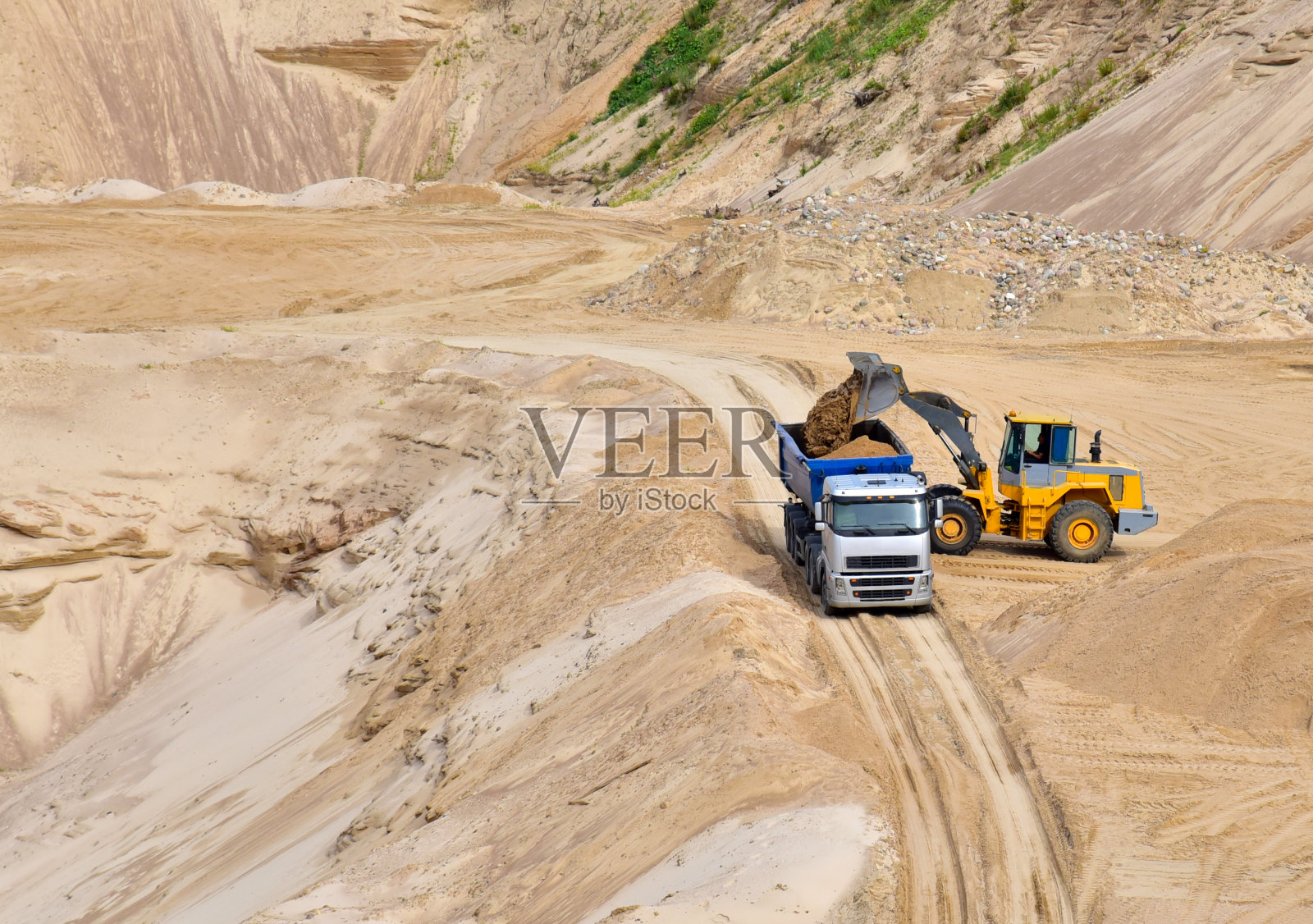 前端装载机在露天采矿场将沙子装入重型自卸卡车照片摄影图片