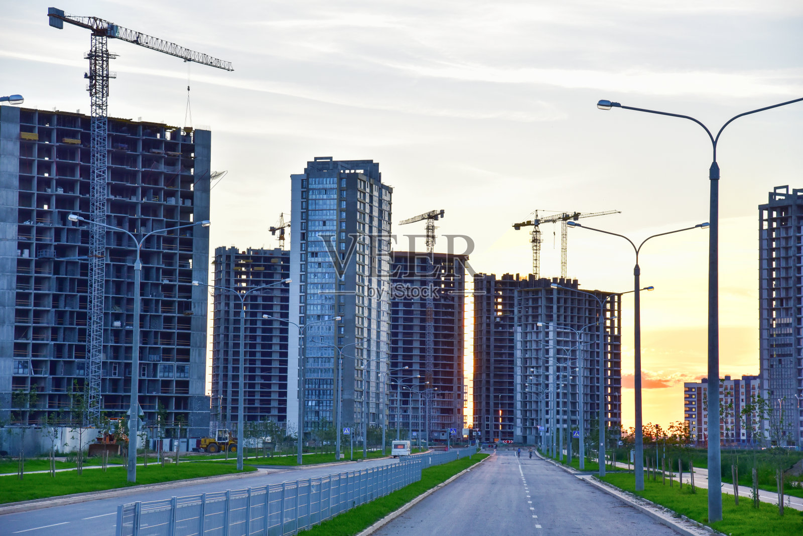 落日背景下的大型建筑工地，塔吊和建筑物照片摄影图片