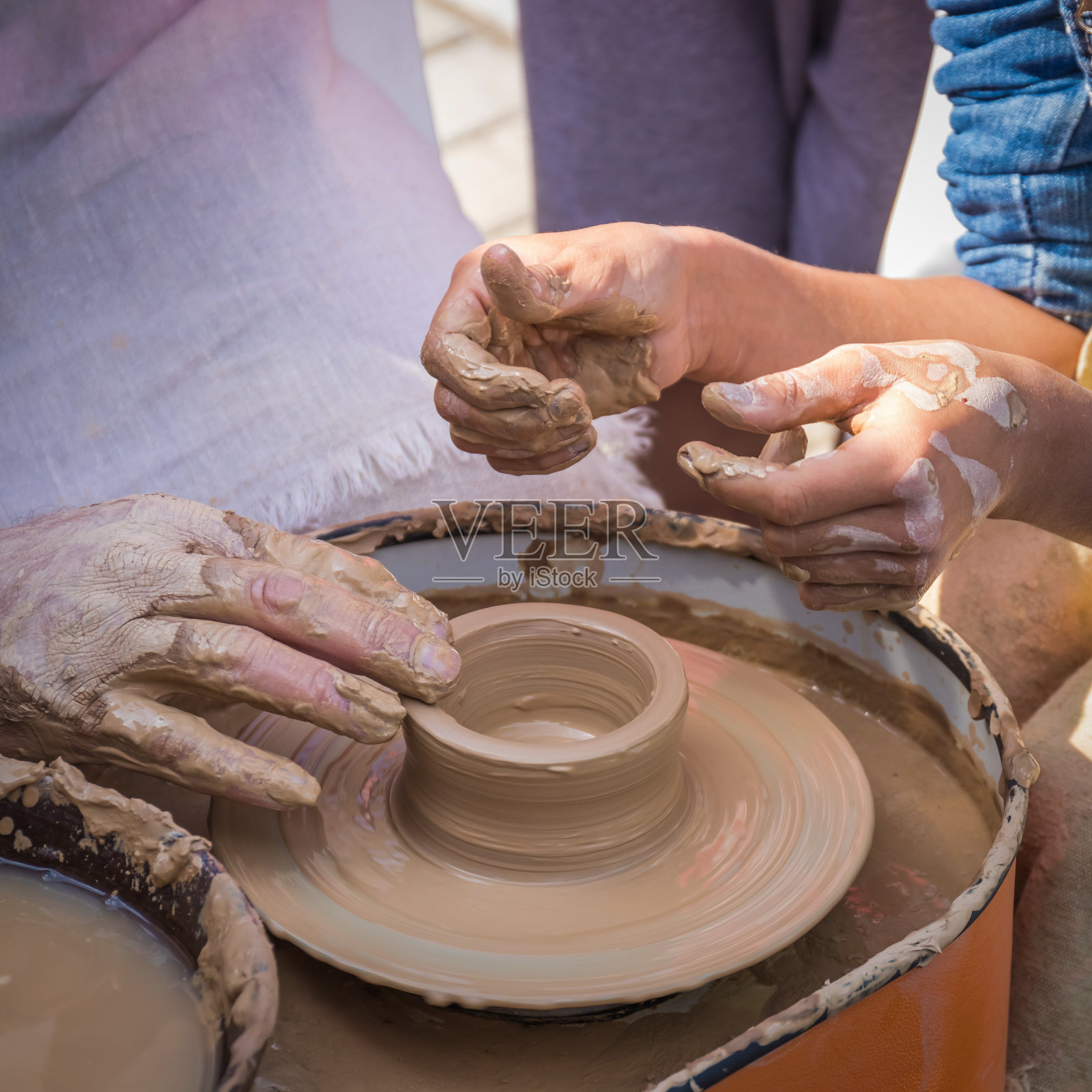 陶艺大师的双手向学生揭示了制作陶土制品的秘密。照片摄影图片