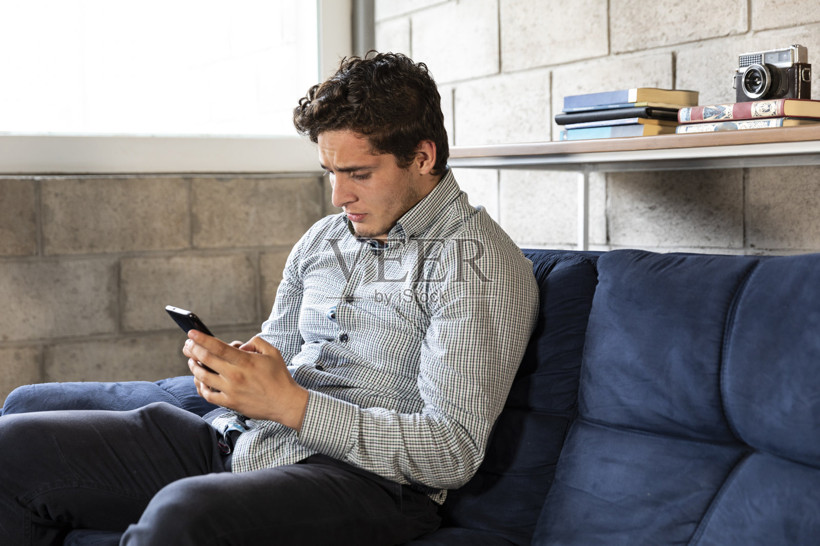 英俊优雅的男人在用手机。在客厅用手机接收好消息照片摄影图片