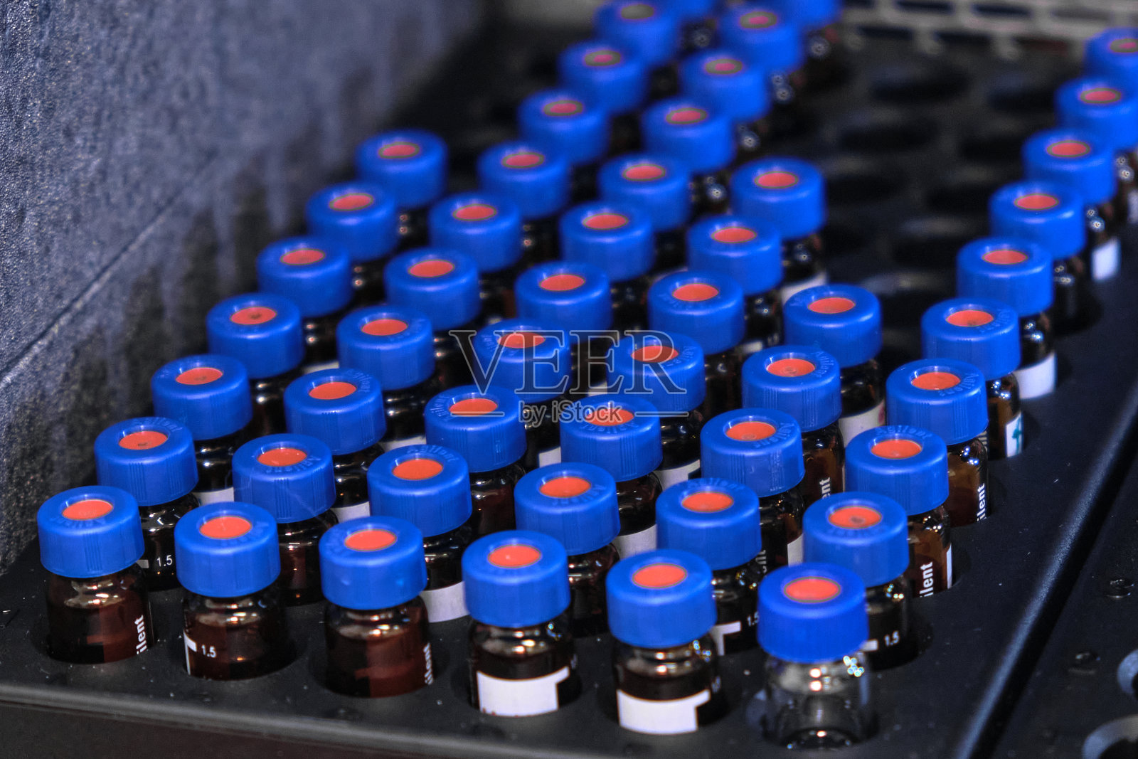 带蓝色瓶盖的玻璃瓶放在带自动进样器的高效液相色谱系统架上。在化学或临床实验室中分离化合物。科学研究工作。医药的发展。照片摄影图片