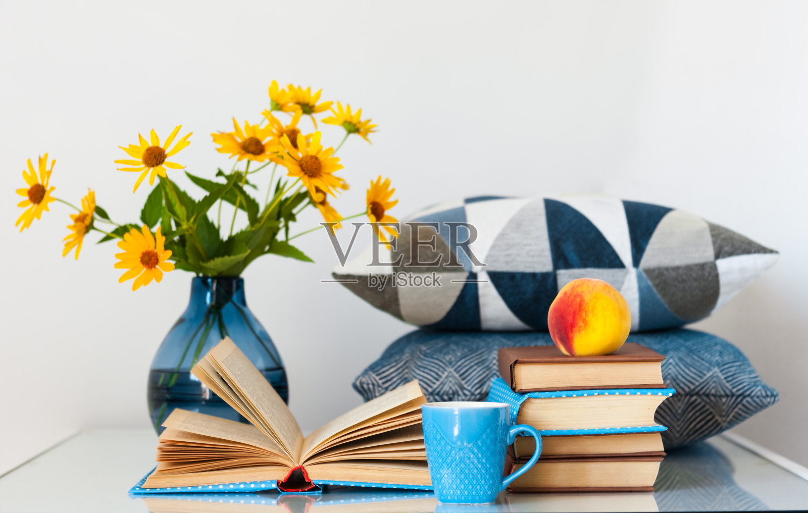 舒适的家庭内部装饰:一堆书和花瓶与黄色的花在桌子上。家庭教育的距离。待在家里的隔离概念照片摄影图片