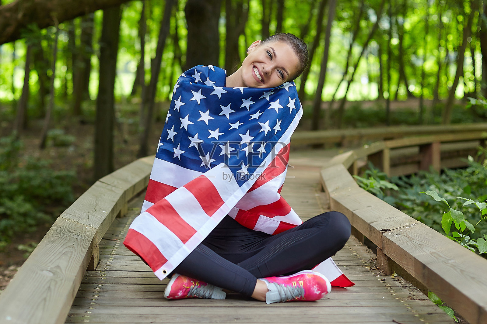 迷人的女孩与美国国旗在森林公园摆姿势照片摄影图片