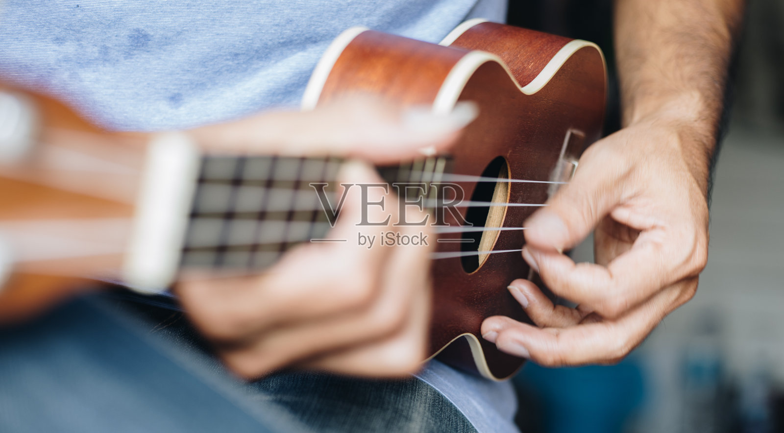 一个年轻人在弹奏尤克里里，概念音乐播放器照片摄影图片