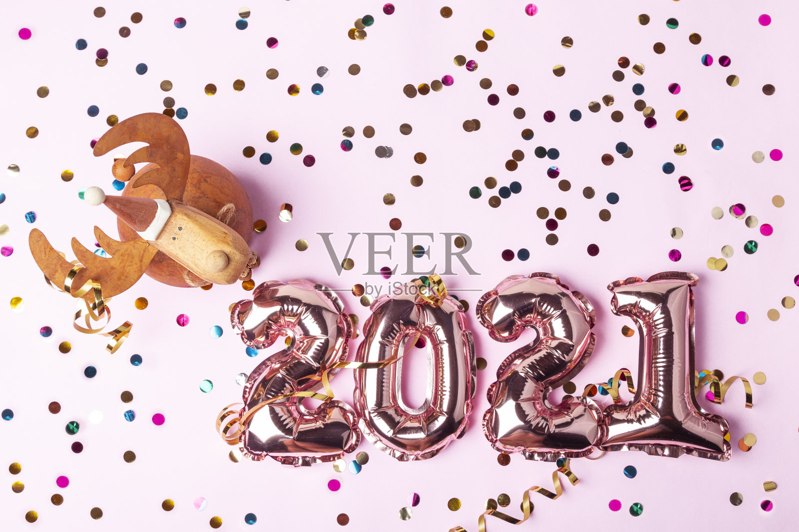 粉色气球，2021年的数字。粉红色的背景上点缀着五颜六色闪亮的五彩纸屑和圣诞小鹿。庆祝新年快乐。平躺，俯视图照片摄影图片