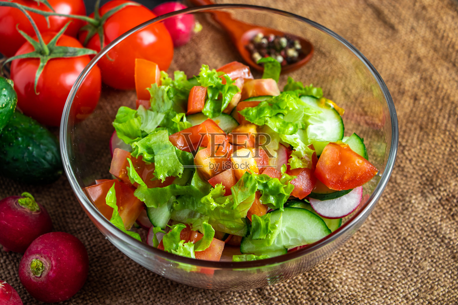 深色背景的玻璃碗里的夏季蔬菜沙拉。有机素食，乡村风味膳食。照片摄影图片