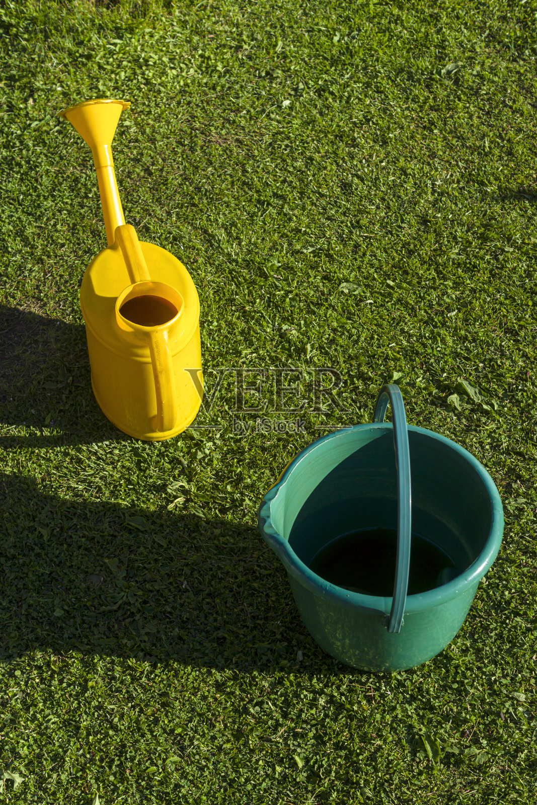 花园浇水罐，准备浇菜地和一个空桶照片摄影图片