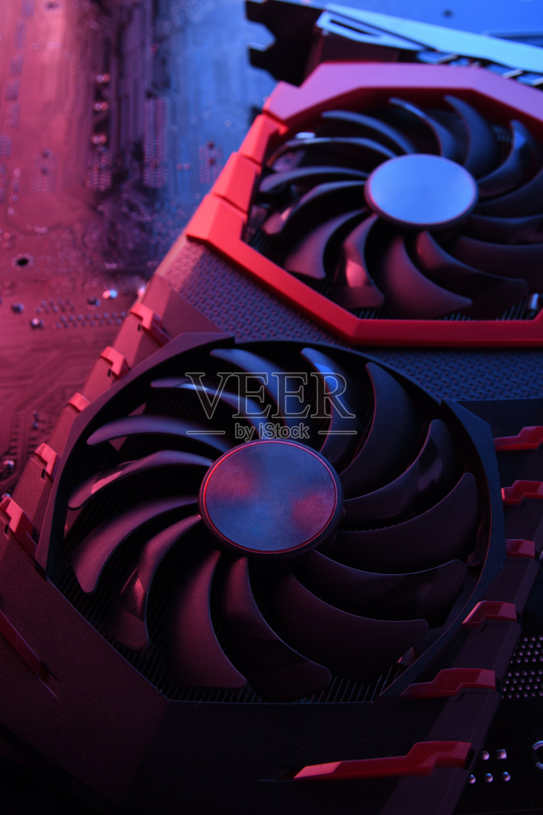 电脑游戏显卡、显卡与两个冷却器在电路板上，主板背景。特写镜头。用红蓝灯照片摄影图片