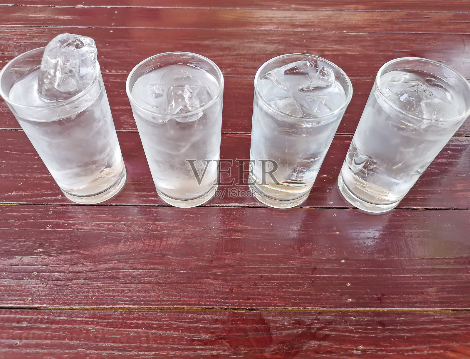 四杯加冰的矿泉水放在红棕色的木桌和复印空间上照片摄影图片