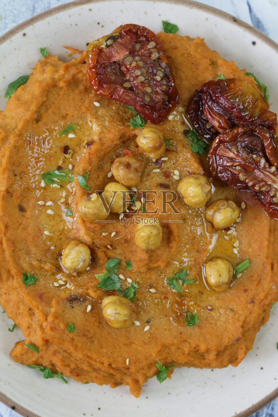 碗的特写图像，含有晒干的番茄鹰嘴豆泥在白色的木头背景，希腊美食，升高的观点照片摄影图片