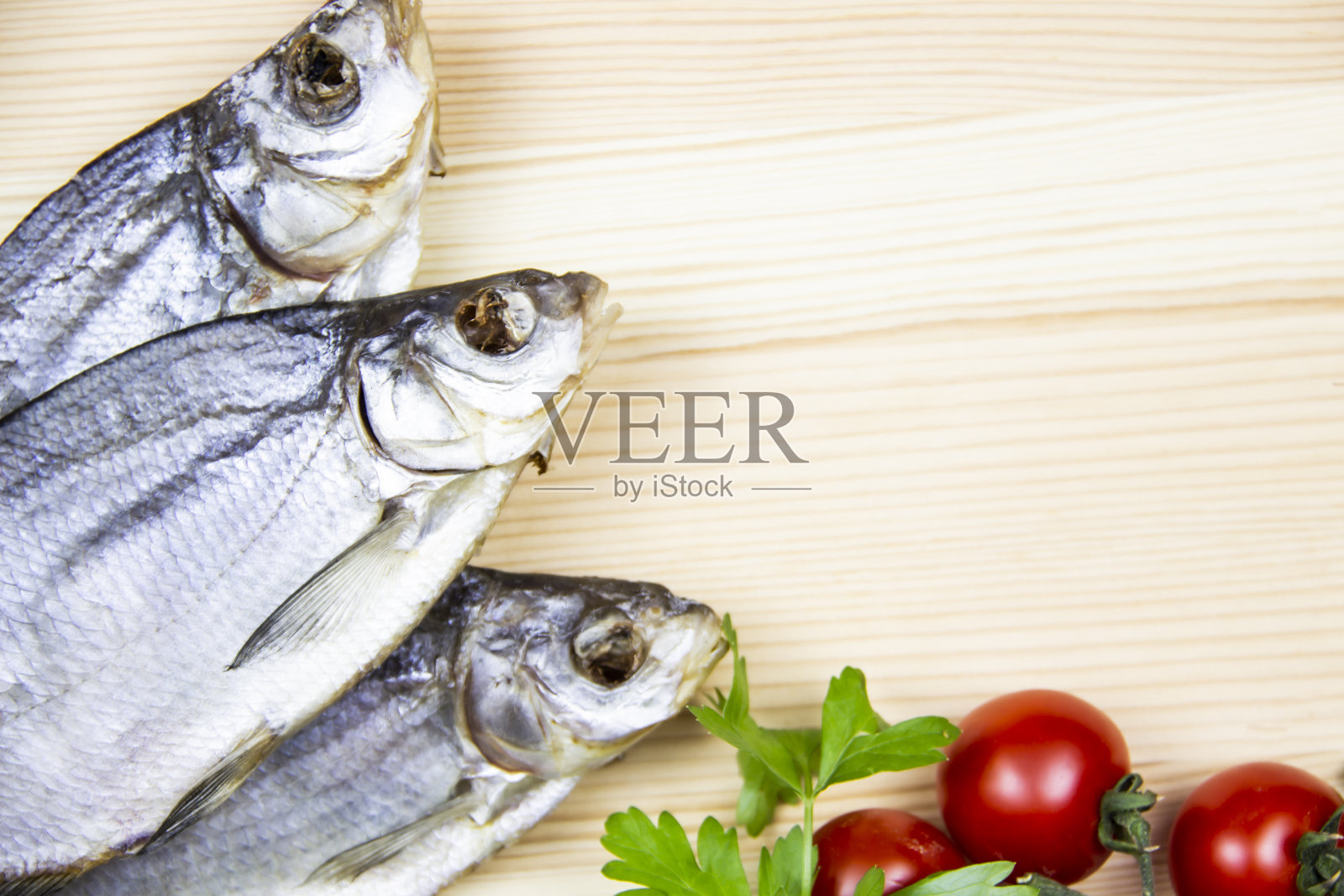 烹饪食物背景与自由的文字空间。用三种干鱼，西红柿，欧芹在浅色的木头背景上组成。顶部视图与复制空间照片摄影图片