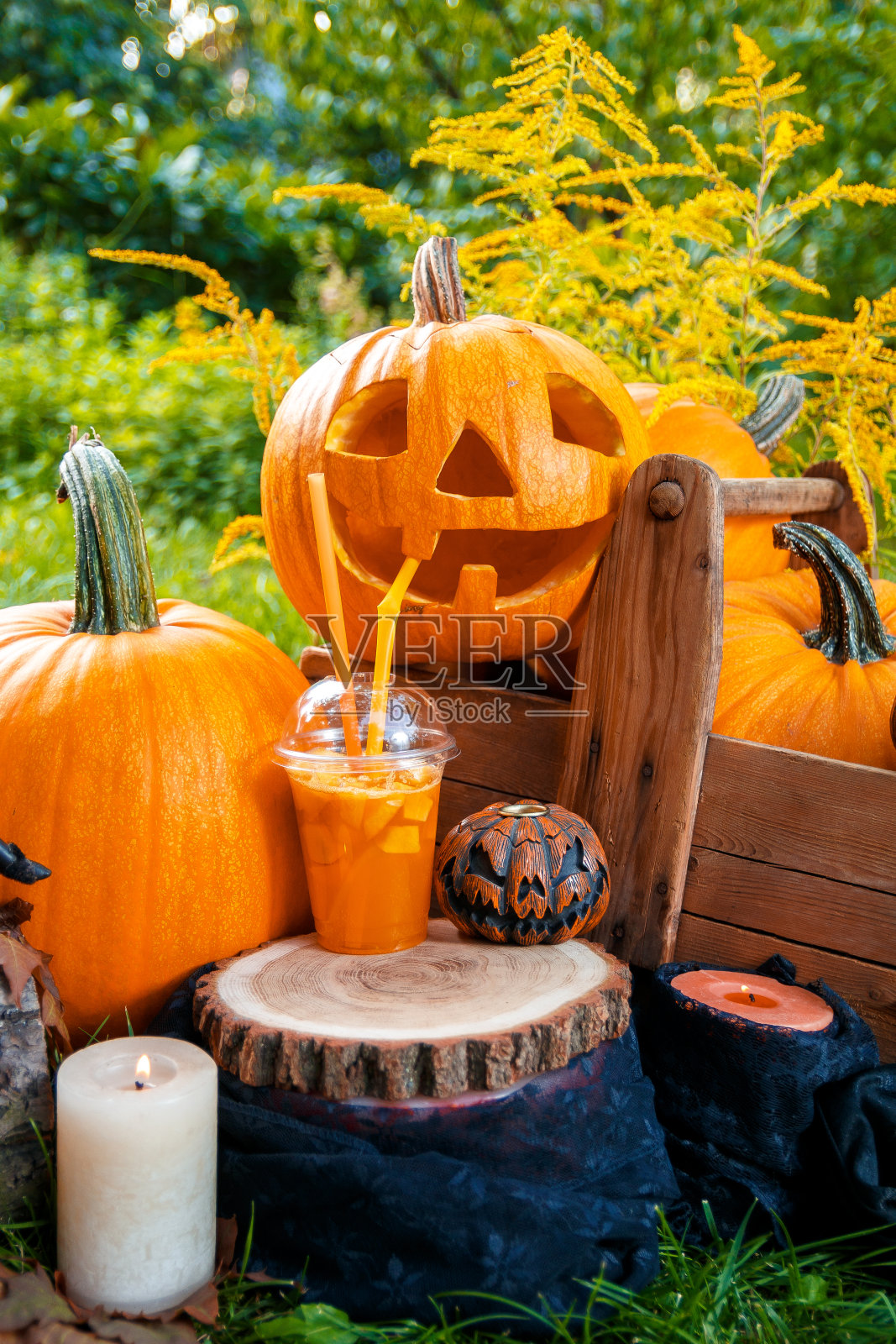 万圣节鸡尾酒附近的南瓜装饰背景。派对用的潘趣酒。南瓜灯正在喝鸡尾酒。照片摄影图片