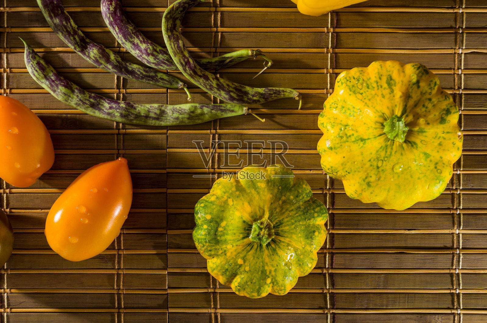 秋季静物-小斑点南瓜，芦笋豆，紫色罗勒，辣椒，黄色和巧克力西红柿在竹席上照片摄影图片