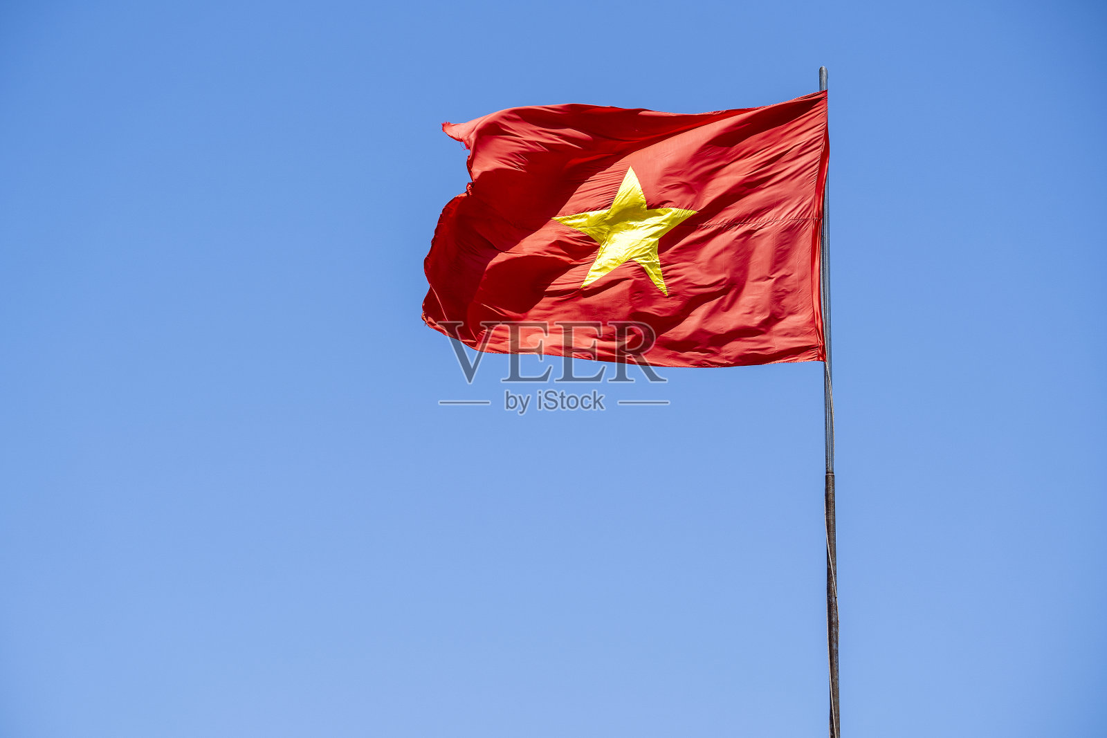 蓝色的天空映衬着红色的越南国旗照片摄影图片