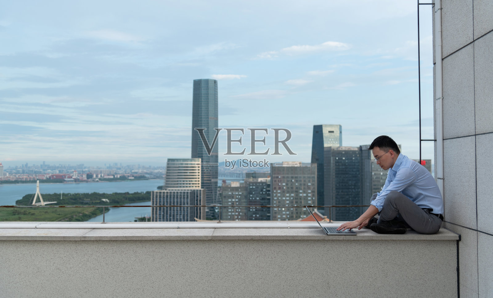 一个商人坐在屋顶上用笔记本电脑照片摄影图片