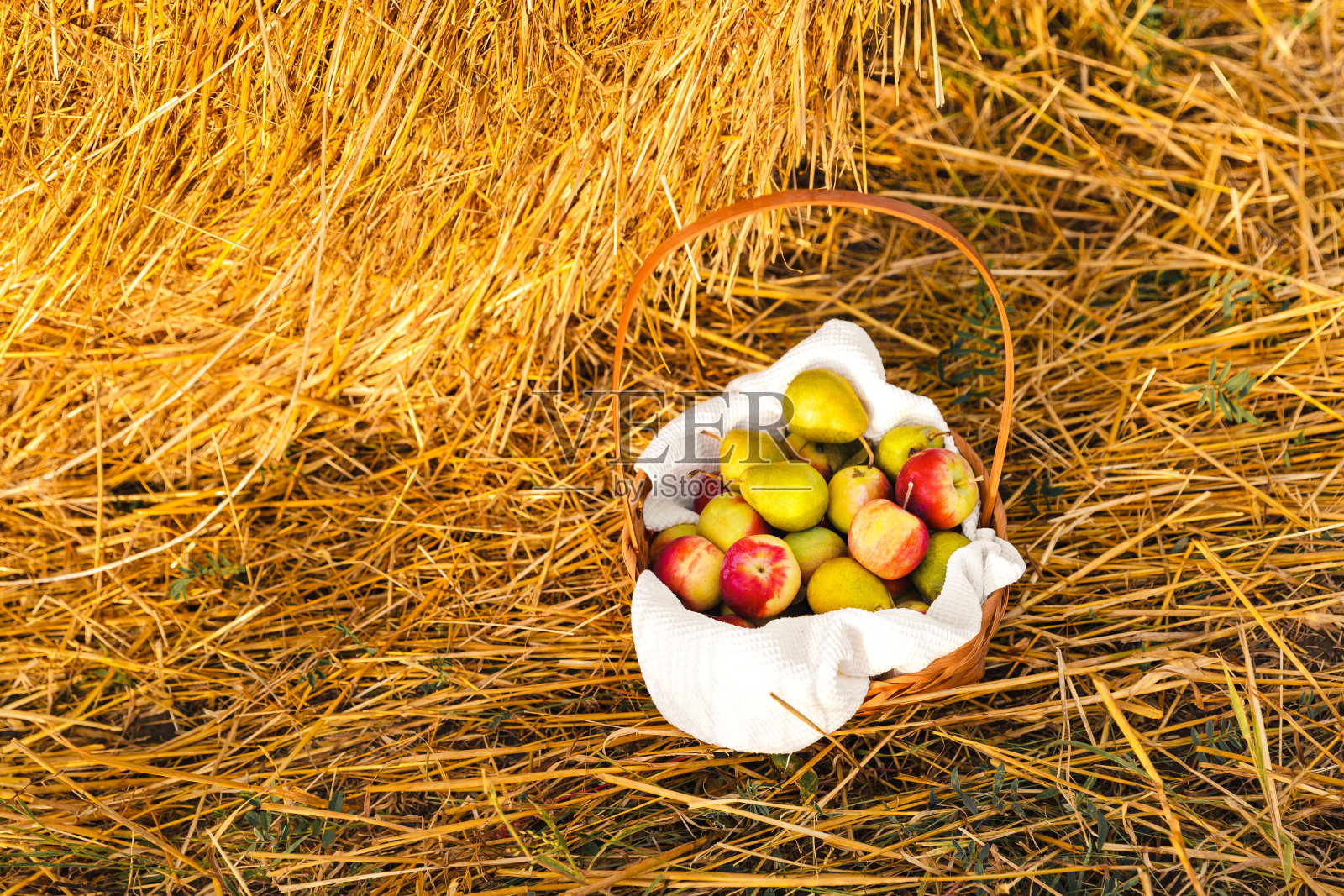 干草棚外的篮子里装着苹果和梨。夏天或秋天在乡村收获。日落时的健康食物照片摄影图片