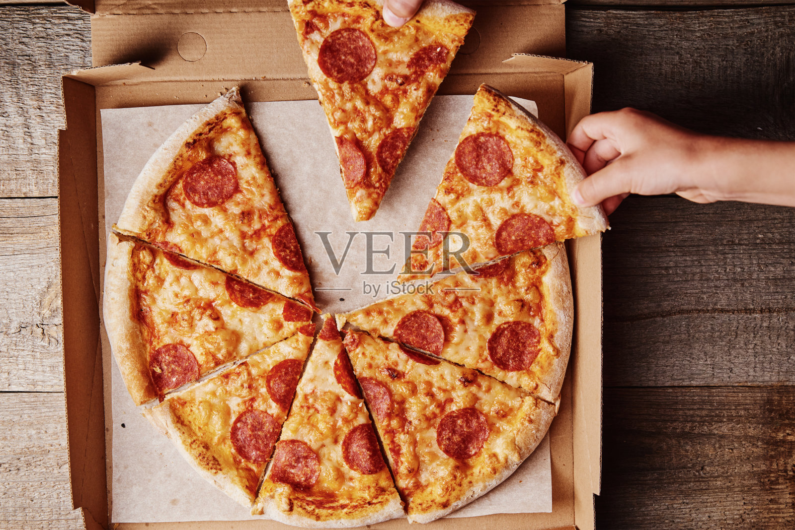 两只手从纸盒里拿起披萨片，俯视图照片摄影图片