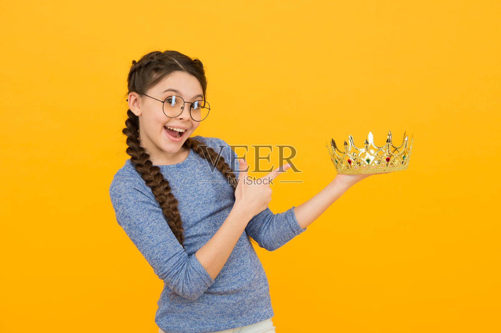 可爱可爱的戴眼镜的女孩。优秀的学生。成功和幸福。聪明的公主。期待已久的回报。聪明的小女孩戴着眼镜。聪明的孩子。公主的概念。快乐微笑的公主照片摄影图片