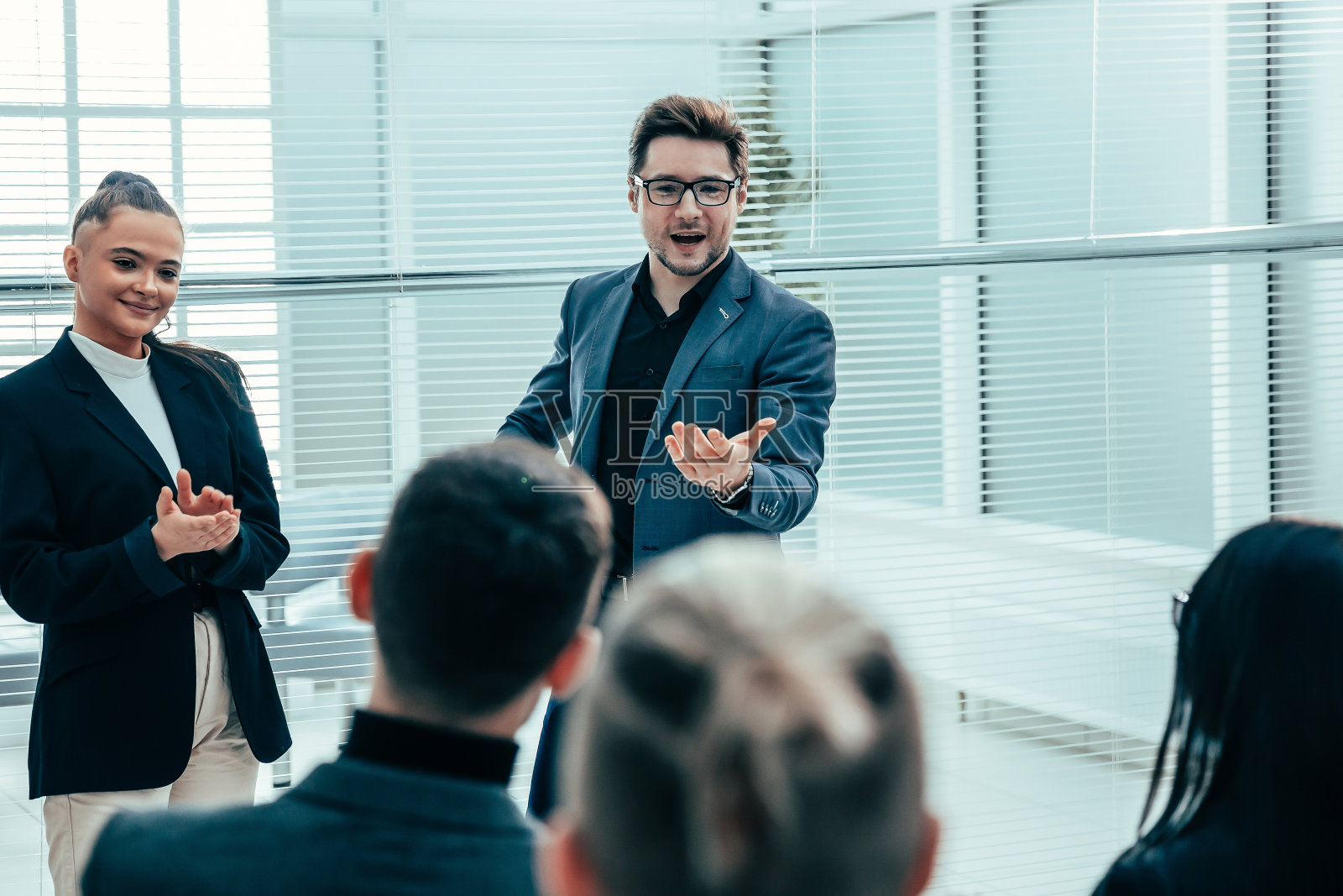 老板在工作会议上祝贺一位年轻员工照片摄影图片