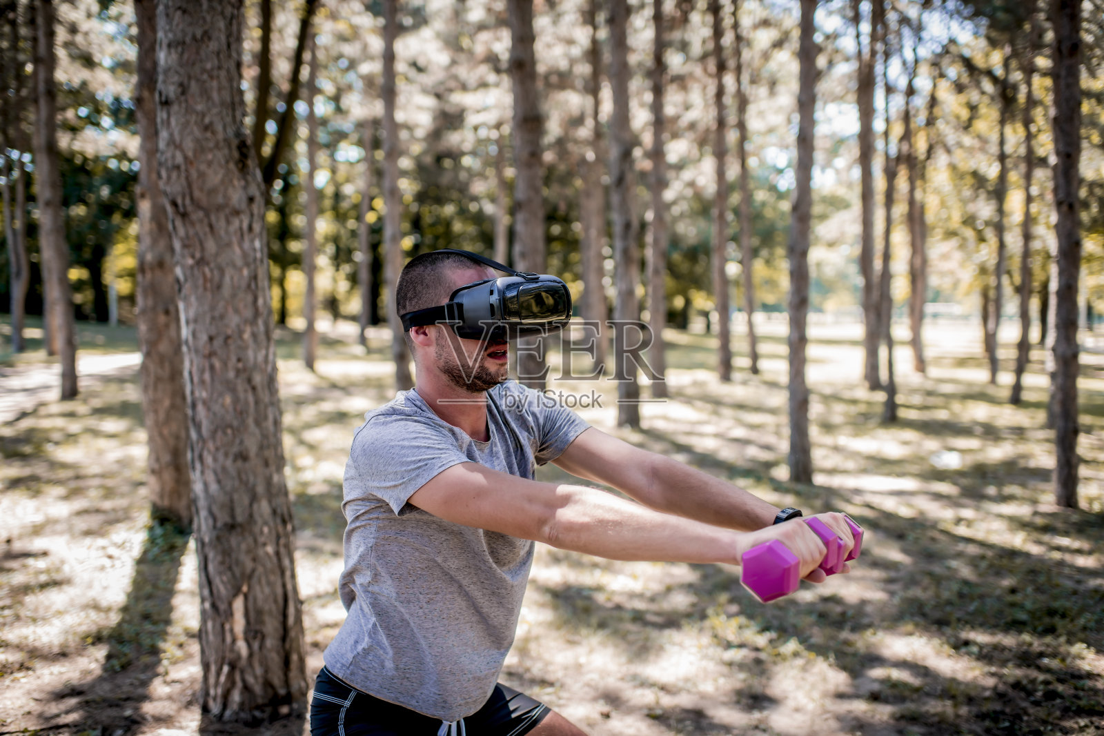 年轻人用哑铃和虚拟现实耳机锻炼照片摄影图片